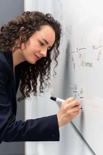 woman writing formula on whiteboard