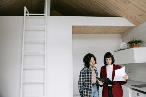 a woman in red coat showing the documents to the woman standing beside her